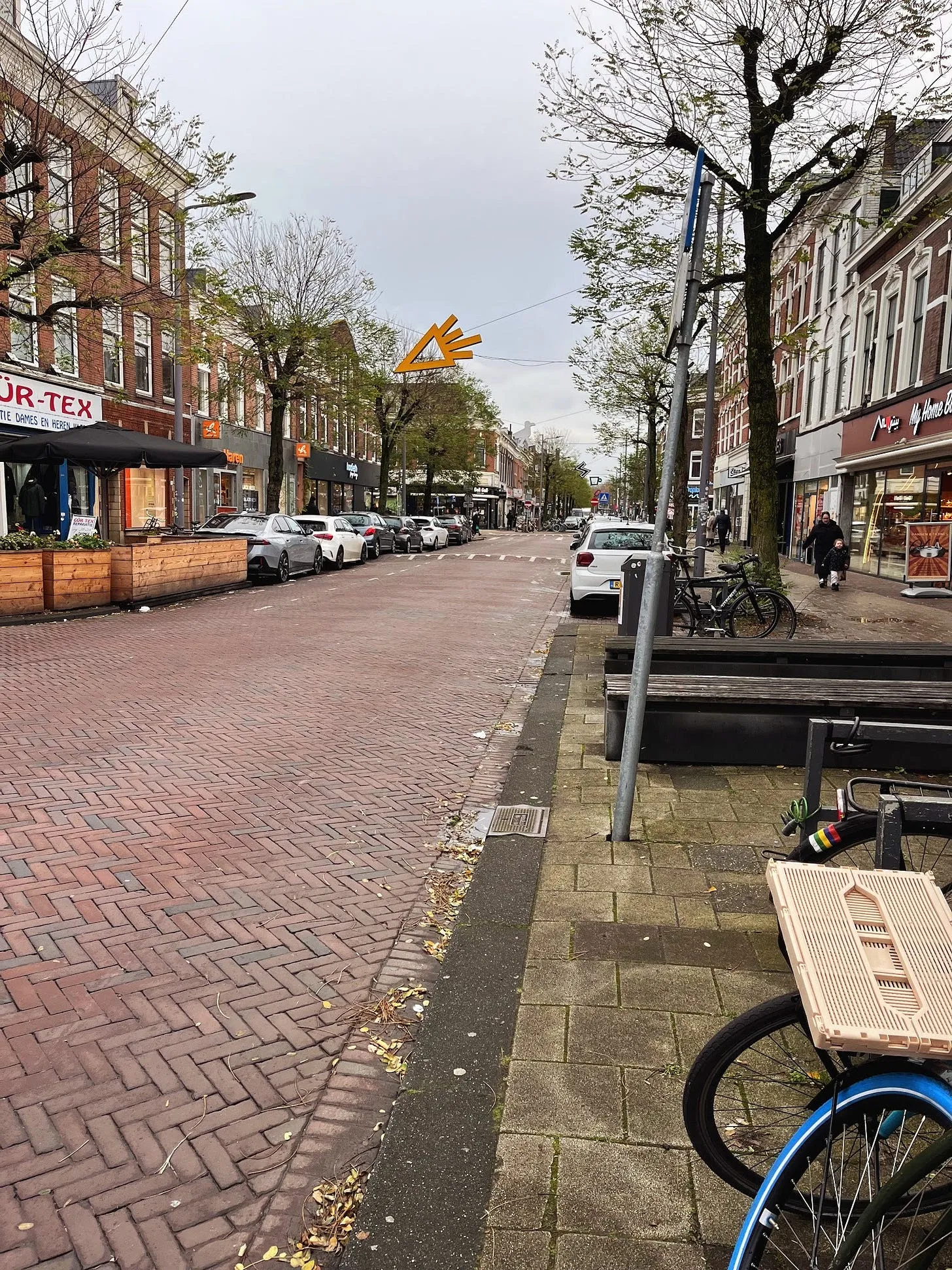 En typisk nederländsk gata i Rotterdam med tegelbeläggning i stället för asfalt, träd, bänkar och cykelparkering.